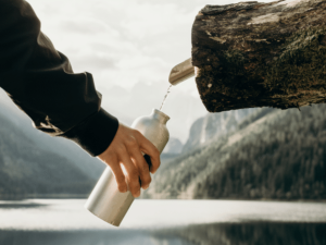 Hand with a reusable bottle being filled with water